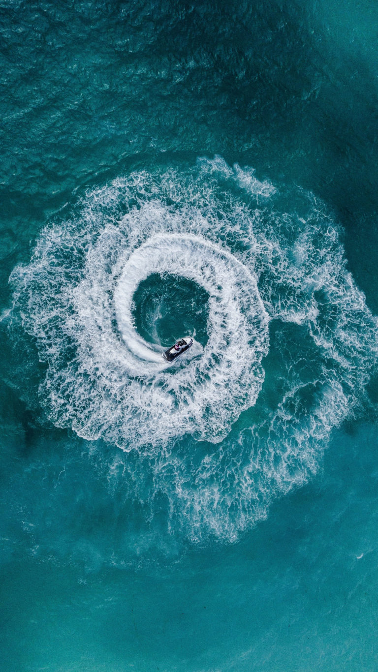 A boat in the water making a circle pattern that resembles a hurricane