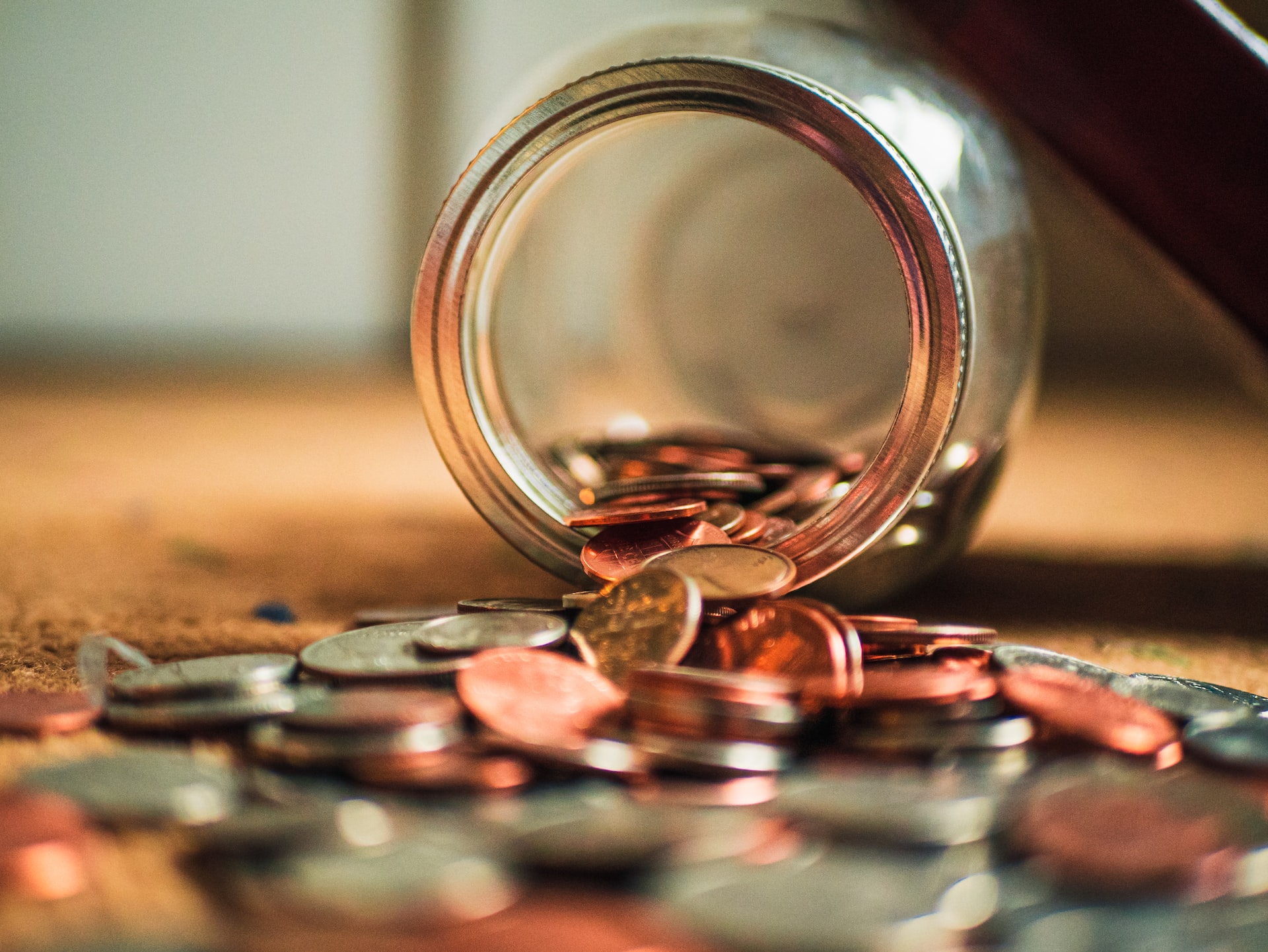 A jar full of coins that has fallen on a table.