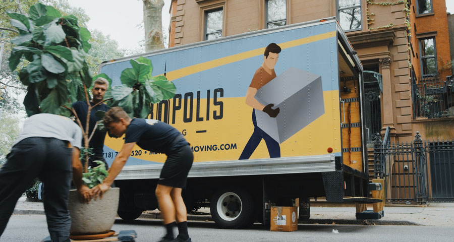 Three young man moving items into a moving truck,