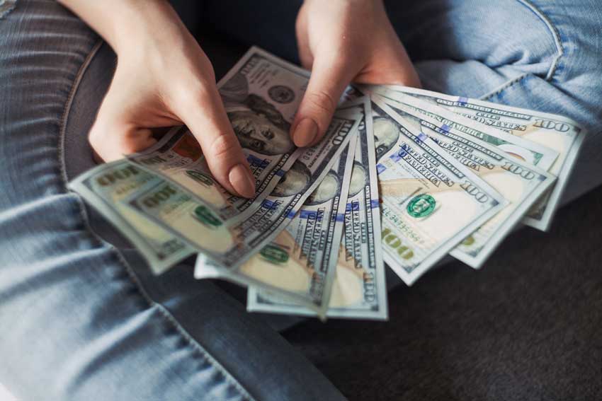 A picture of a person counting hundred dollar bills.