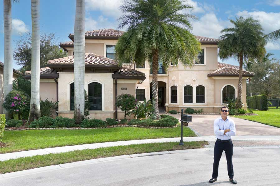 A real estate agent in front of a large home in Delray Beach, FL